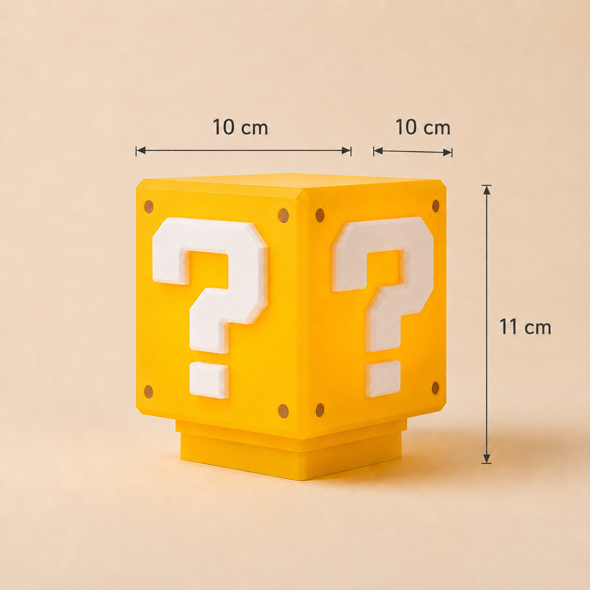 A yellow block-shaped product with white question marks on the front, shown on a beige background with overlaid dimension lines and labels reading 10 cm, 10 cm, and 11 cm.
