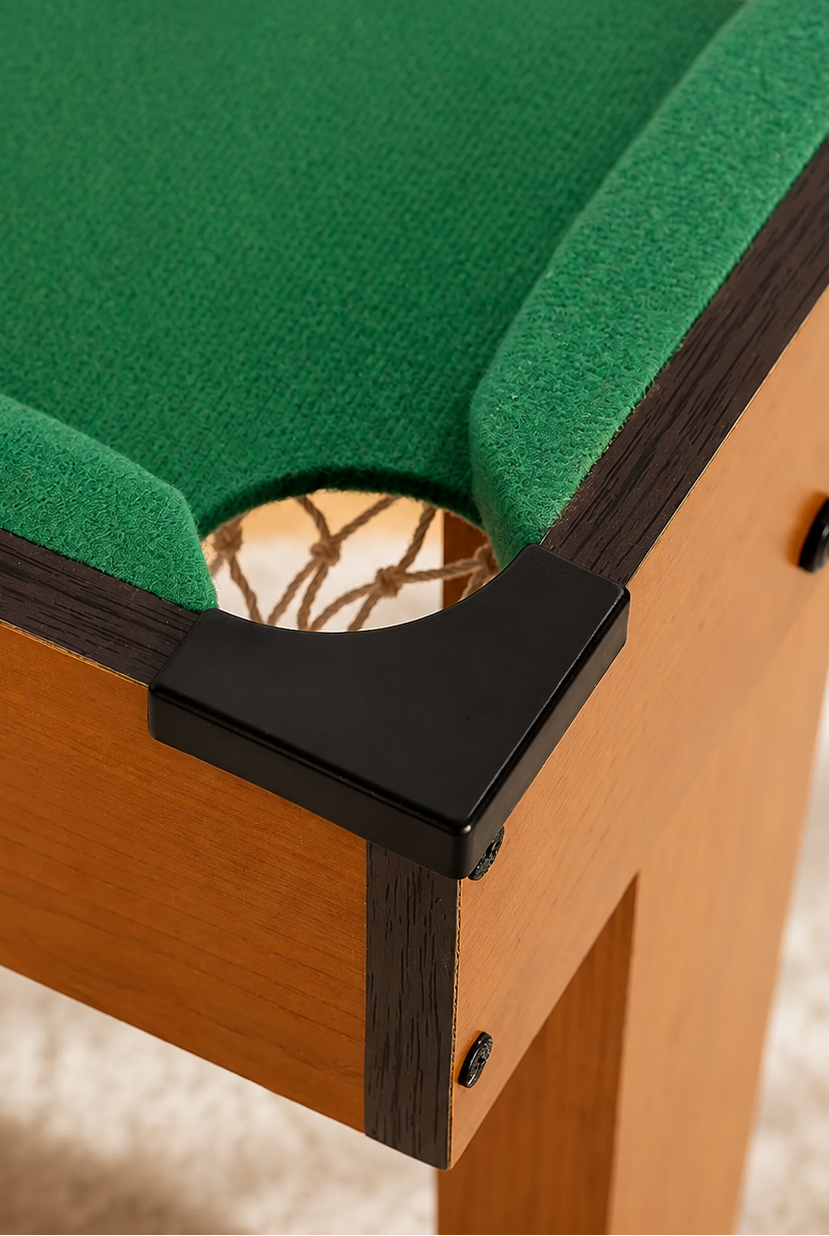Close-up of a wooden pool table corner with green felt lining, dark trim, and a black corner guard in a softly blurred indoor setting.